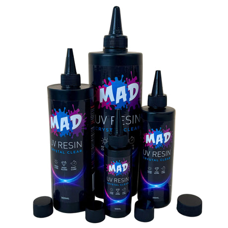 Three black squeeze bottles of MAD UV Resin Crystal Clear in different sizes, with nozzels on top and their caps removed and placed in front of them.